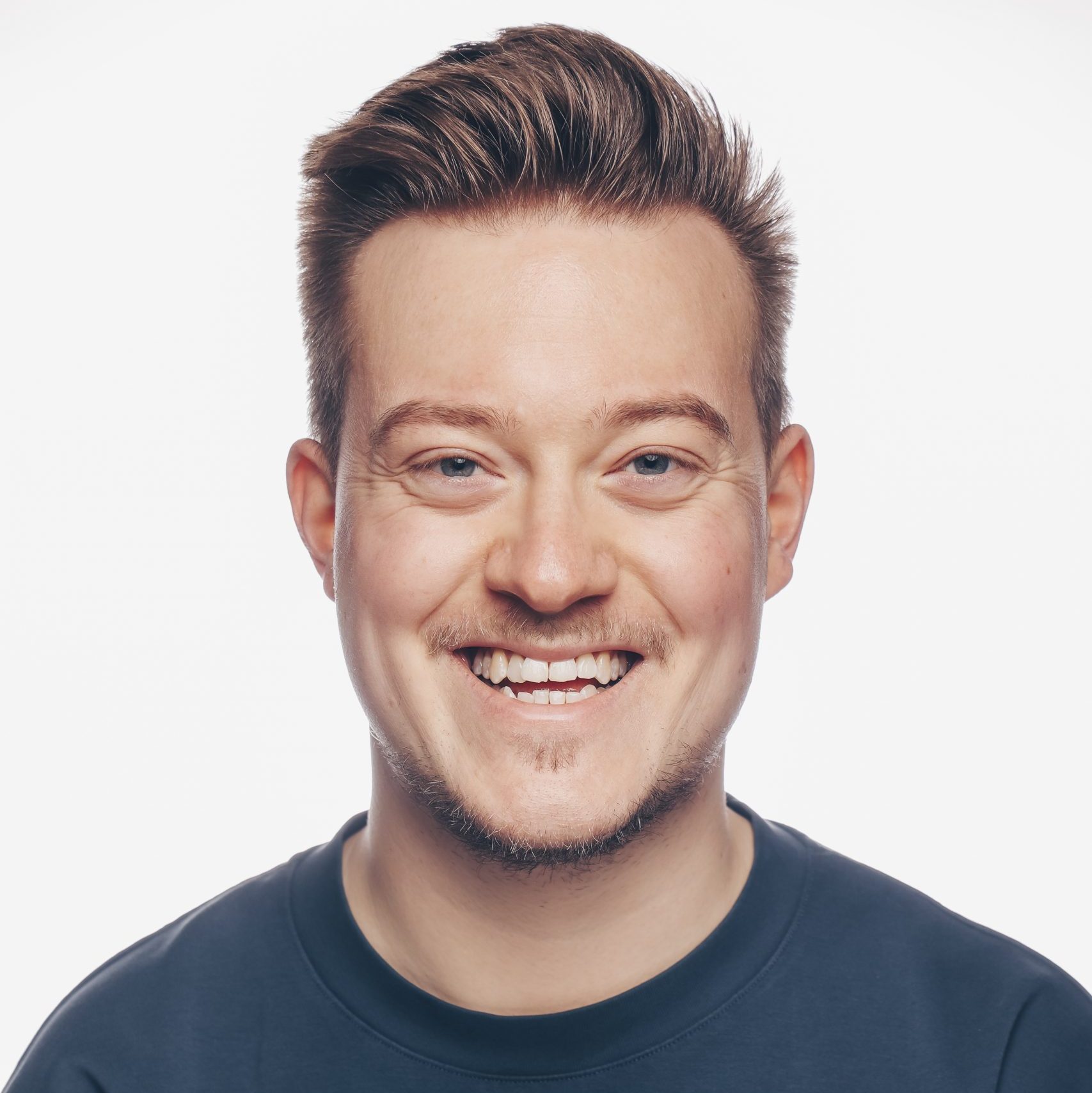 Portrait von René Schaar. Er trägt ein blaues Shirt und lächelt.